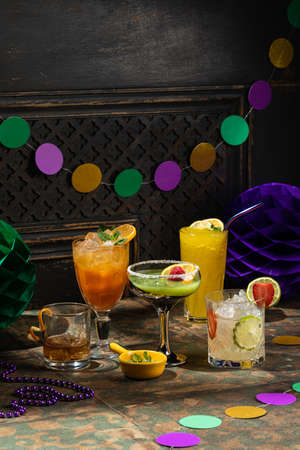 Alcoholic beverage cocktails, purple, green and gold Mardi Gras beads, masks decoration on dark rustic background, festive holiday conceptの写真素材