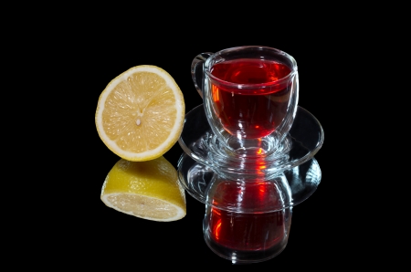 Red tea and lemon with a reflection on a black backgroundの写真素材