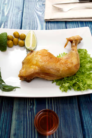 chicken leg on a plate on the blue tableの写真素材
