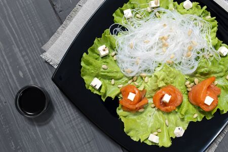 salad of salmon and rice noodles on a black plateの写真素材
