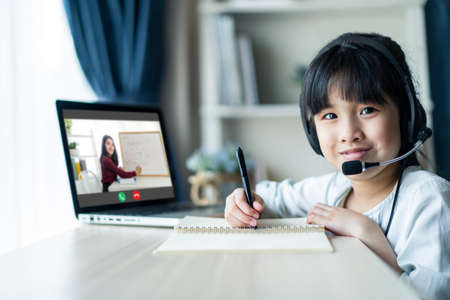 Homeschool Asian little young girl learning online class from school teacher by remote internet...