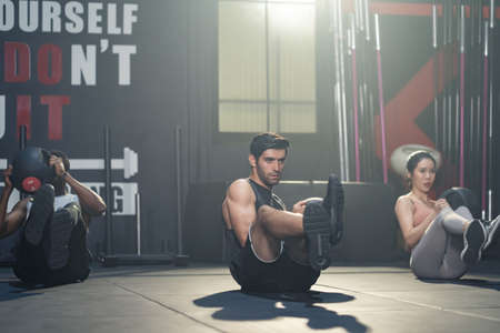 Group of multiethnic fitness trainer workout, sitting play medicine ball in gym or stadium. Athlete...