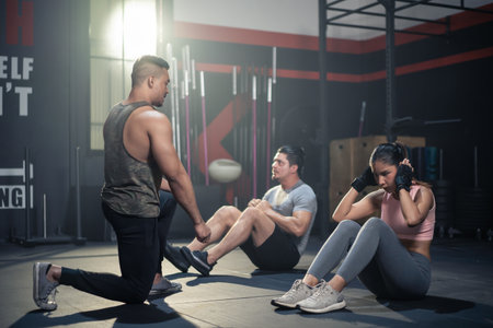 Asian Fitness trainer teach and motivate young beautiful sportsman and woman sit-up on floor for abs...