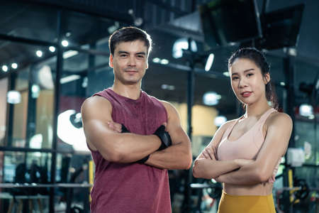 Portrait of Active athlete people standing and crossing arms in gym. Sportman and woman with six pack abs look at camera after workout exercise for health care and build muscle in fitness club stadiumの写真素材