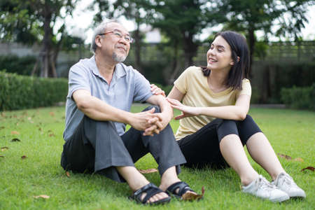 Asian girl daughter take care of senior elderly grandfather in garden. Attractive young beautiful...