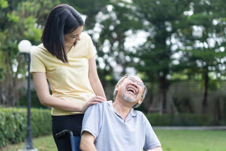 Asian happy Senior retired grandfather enjoy outdoor at green park. Attractive girl daughter pushing...