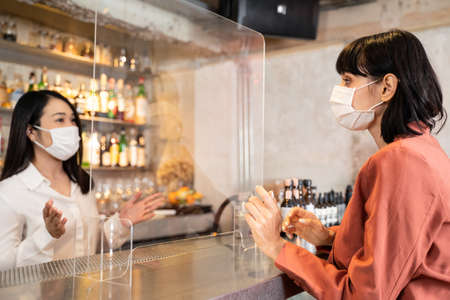 Woman customer receiving food from waitress with face mask on counter then next customer come and...