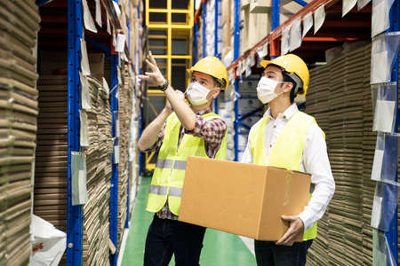 Woman worker hold tablet talking to man in warehouse store. Male and female engineers people wear...