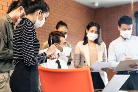 Group of Asian team business people working in office with new normal lifestyle concept. Man and woman wear protective face mask and keep distancingの写真素材