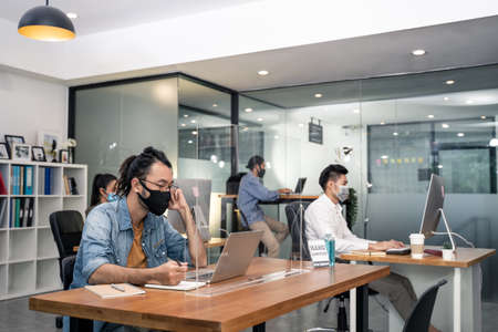 Group of Asian team business people working in office with new normal social distancing lifestyle...