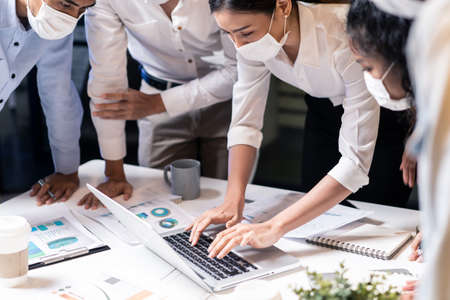 Group of Asian team business people working in office with new normal social distancing lifestyle concept. Man and woman wear protective face mask and keep distancing to prevent virus in companyの写真素材