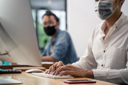 Group of Asian team business people working in office with new normal social distancing lifestyle concept. Man and woman wear protective face mask and keep distancing to prevent virus in companyの写真素材