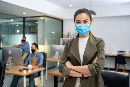 Asian businesswoman in formal suit wear facemask and work at workplace. Attractive female employee office worker discuss about company plan dururing pandemic.の写真素材