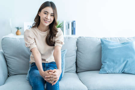 Portrait of Asian beautiful woman sit on sofa in living room at home. Attractive young female...