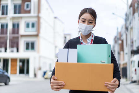 Asian business woman wear face mask after unemployment from company. Young attractive girl employee...