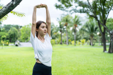 Asian young sport woman stretch body warm up before exercise in park. Active beautiful athlete girl...