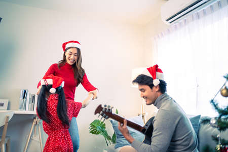 Asian lovely family member enjoy sing Christmas song together at home. Young little daughter feeling happy and excited to celebrate holiday Christmas Thankgiving party together with parents in house.の写真素材
