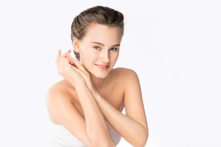 Beautiful young Caucasian woman with clean fresh white skin touching own face softly in beauty pose. Girl touching with finger with eyes opening. Facial treatment, cosmetology, spa, make up concept.の写真素材