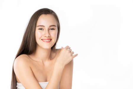 Beautiful Young Caucasian woman, clean fresh white skin face in beauty pose. Girl touching shoulder with finger isolated background. Facial treatment, cosmetic, spa, make up, plastic surgery concept.の写真素材