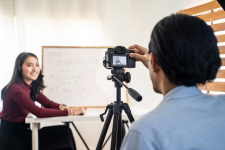 Asian school woman teacher working from home teaching online internet class to student studying from home. Man using camera to record girl digital live. Remote education class during covid19 pandemic.の写真素材