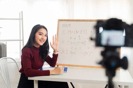 Asian school woman teacher working from home teaching online math subject to student studying from home. Girl using camera to record live on internet. Remote education class during covid19 pandemic.の写真素材