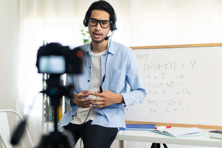 Asian school male teacher working from home teaching online math subject to student studying from...