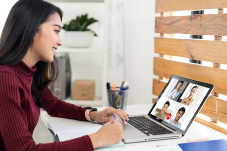 Asian business woman talking to colleague team about plan in video conference. Group of business people using computer for online meeting in video call conference. New normal smart working from home.の写真素材