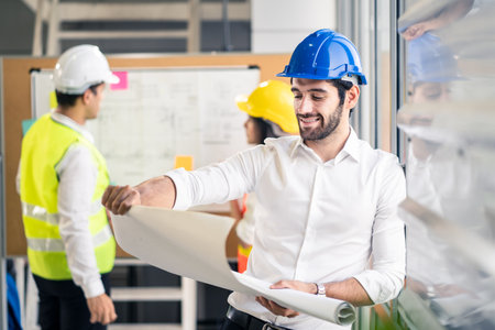 Caucasian man hold blueprint drawing while his team members looking project area. Young engineer group of home building member discuss for project planning.People brainstorm teamwork idea of structureの写真素材