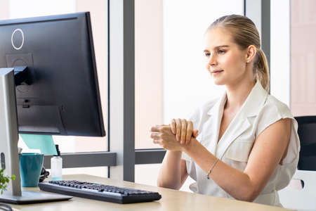 Caucasian young office woman use hand sanitizer gel for hand hygiene before typing computer keyboard. Alcohol help to avoid get sick from coronavirus. Covid-19 outbreak healthcare sickness concept.の写真素材