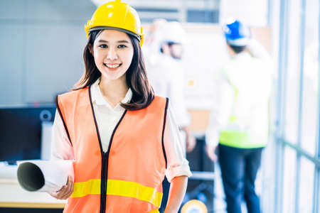 Asian young engineer group of home building member discuss for project planning. Smile woman hold blueprint drawing while team members give some advice. People brainstorm for idea of structure controlの写真素材