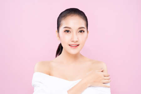 Beautiful Young Asian woman with clean fresh white skin face in beauty pose. Girl touching shoulder with finger isolated background. Facial treatment, cosmetic, spa, make up, plastic surgery concept.の写真素材