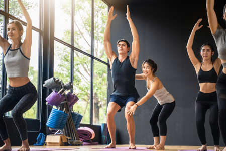 Group of multi ethnics people learning Yoga class in fitness club. Female Caucasian instructor...