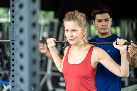 Young fit sport Caucasian blond hair woman working out in gym or fitness club. The athletic girl...