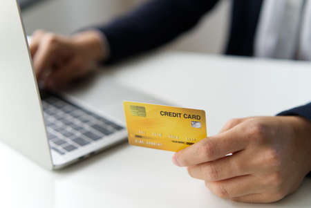 Smart handsome young business man holding dummy credit card and typing on laptop paying or shopping...