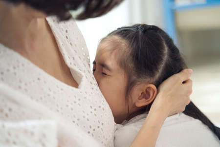 Close up view of Asian young little girl is crying and her mother consoling by touching on head...