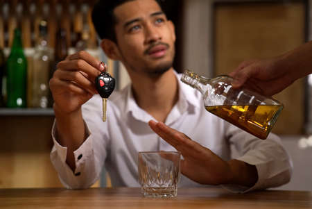 Drink no drive, say no for safety, no more alcohol concept. The man sitting in restaurant holding...