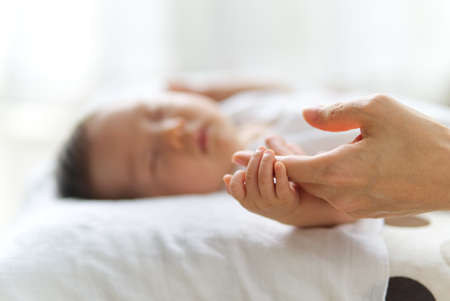 Close up shot of sleeping cute newborn baby hand holding the hand of mother. Pure love between mother and baby.  New family and baby protection from mom concept.の写真素材