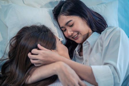 Asian beautiful lesbian couple lying down on bed and hugging each other. Attractive romantic girl...