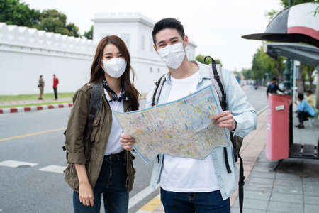 Portrait of Asian couple wear mask, travel in city for honeymoon trip. New marriage man and woman...