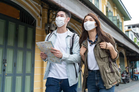 Asian romantic couple wear mask, travel in the city for honeymoon trip. New marriage man and woman...