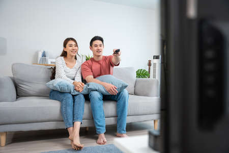 Asian young loving couple watch movie together in living room at home. Attractive romantic new...