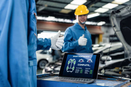 Close up of Automotive mechanic running diagnostics software on tablet. Asian young vehicle service...