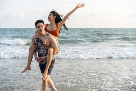 Asian young man and woman having fun, playing on the beach together. Attractive new marriage people feel happy while walking and running at seaside enjoy holiday honeymoon trip in tropical sea island.の写真素材