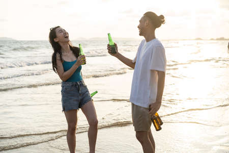 Asian loving young man and woman having party on the beach together. Attractive romance couple singing and dance while walking and running at seaside enjoy holiday vacation trip in tropical sea islandの写真素材