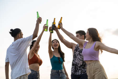 Group of Asian young man and woman having party on the beach together. Attractive friends singing and dancing while walking and running at seaside enjoy holiday vacation trip in tropical sea island.の写真素材