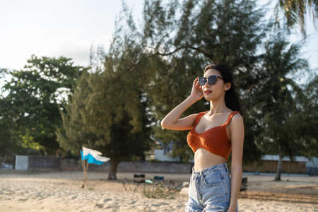 Portrait of Asian young woman standing on beach during summer time. Attractive female traveler feel happy and relax taking a deep breath while travel for holiday vacation trip in tropical sea island.の写真素材