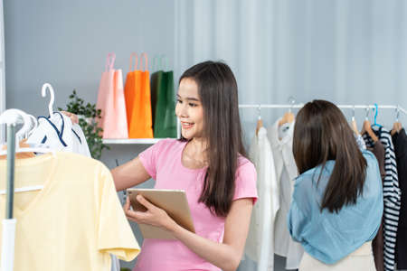 Asian woman friends couple packing clothes order into box for customer. Young attractive business...
