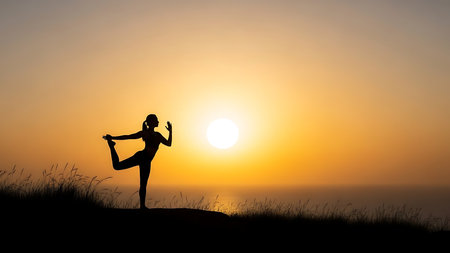 A woman in a yoga pose silhouetted against a vibrant sunset sky, symbolizing peace and well-being.の素材