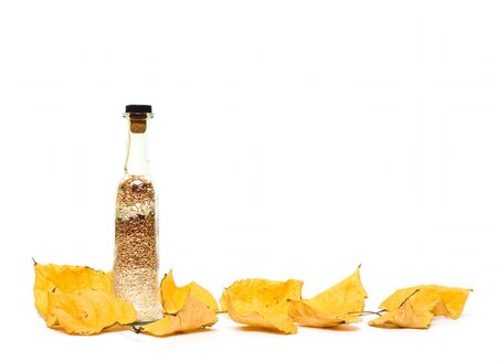 Bottle with groats and fall leafs isolated on whiteの写真素材