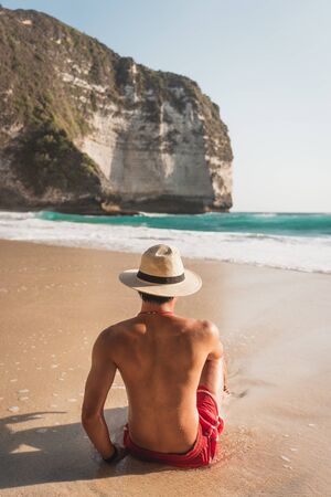 A man sit on Kelingking beach, Nusa Penida island in Indonesia, Asiaの写真素材